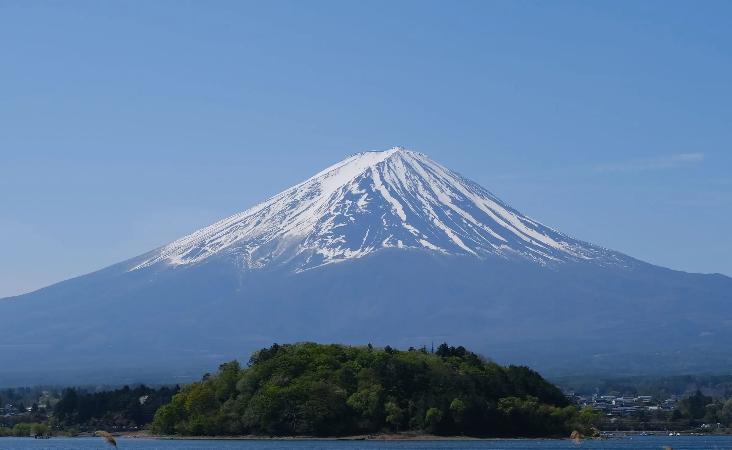 Mount Fuji under a clear blue sky, across a lake